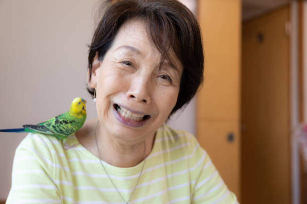 istock Senior woman playing with pet bird 1320429444