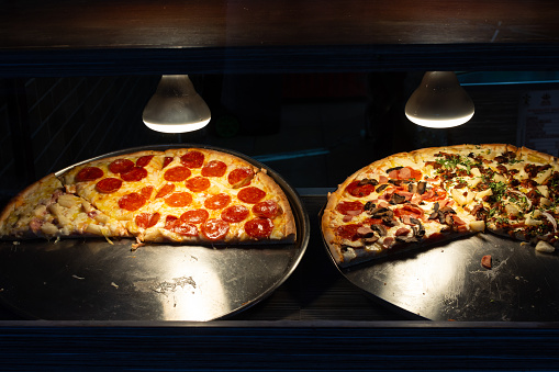 Pizzas in pizzeria stained glass, illuminated with artificial light.