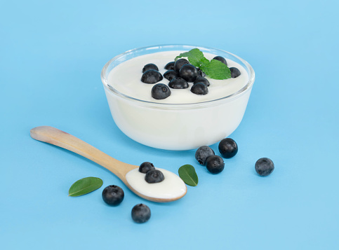Close up yogurt with fresh blueberries  fruit in glass bowl  on blue background