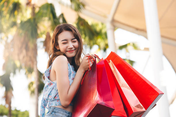 Young adult asian woman with shopping bags at department store. Wellbeing single shopaholic lifestyle on holidays. Happy young adult asian woman with shopping bags at department store on day. thailand mall stock pictures, royalty-free photos & images