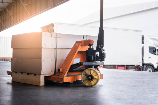 istock Package Box on Pallet with Hand Pallet Truck. Cargo Truck Parked Loading at Dock Warehouse. Shipment. Freight Truck Transport and Logistics. 1320435040
