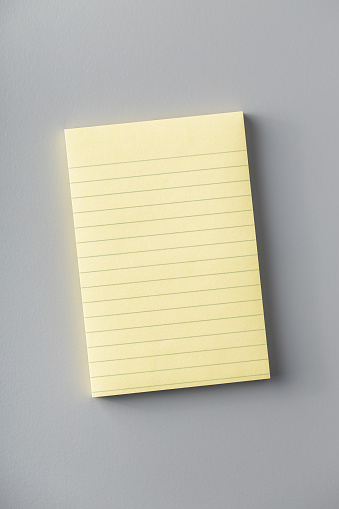 Blank sticky paper notepad on gray table. Top view.