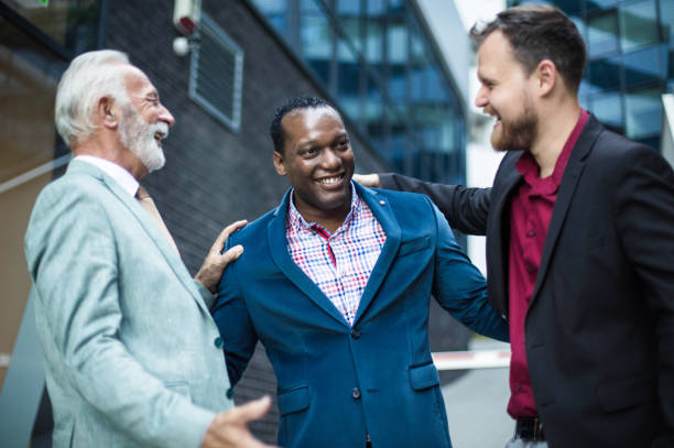 istock Three smiling business men talking on street. 1320435312