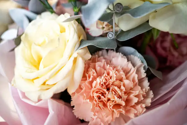 bouquet of the pastel color flowers, yellow, white and pink. roses and carnations in floral composition. a gentle traditional gift for a woman.