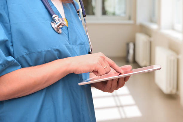 istock A doctor with a stethoscope around his neck holds a tablet computer in his hand and leads a finger across the screen 1320442592