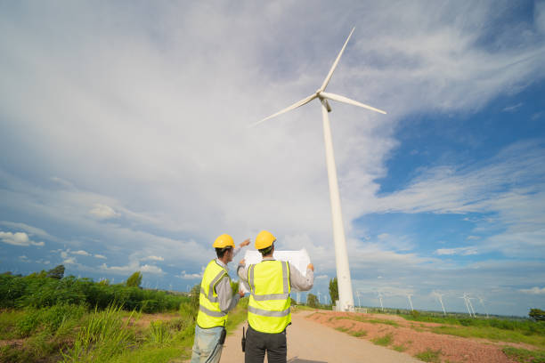 istock Teamwork of Asian windmill engineer group, worker working, holding a plan on site at wind turbines field or farm, clean energy source. Eco technology for electric power. industry nature. People 1320444853