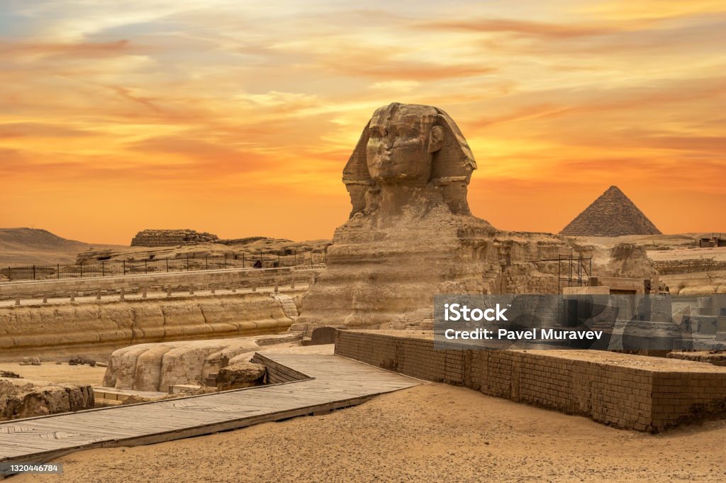 Landscape with Egyptian pyramids, Great Sphinx and silhouettes Ancient symbols and landmarks of Egypt for your travel concept to Africa in golden sunlight. Landscape with Egyptian pyramids, Great Sphinx and silhouettes Ancient symbols and landmarks of Egypt for your travel concept to Africa in golden sunlight. The Sphinx in Giza pyramid complex at sunset The Sphinx Stock Photo