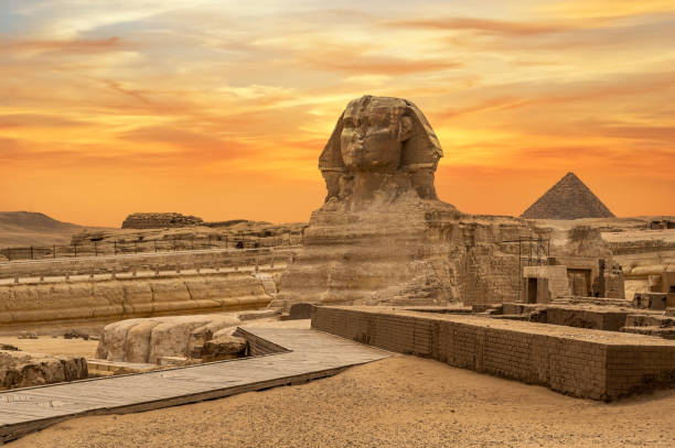 Landscape with Egyptian pyramids, Great Sphinx and silhouettes Ancient symbols and landmarks of Egypt for your travel concept to Africa in golden sunlight. Landscape with Egyptian pyramids, Great Sphinx and silhouettes Ancient symbols and landmarks of Egypt for your travel concept to Africa in golden sunlight. The Sphinx in Giza pyramid complex at sunset great pyramid of khufu stock pictures, royalty-free photos & images