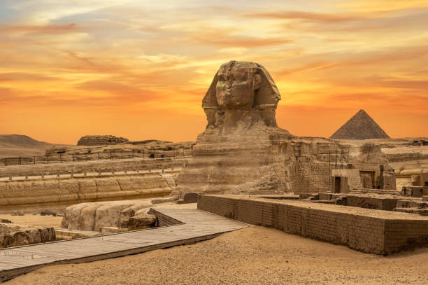 Landscape with Egyptian pyramids, Great Sphinx and silhouettes Ancient symbols and landmarks of Egypt for your travel concept to Africa in golden sunlight. Landscape with Egyptian pyramids, Great Sphinx and silhouettes Ancient symbols and landmarks of Egypt for your travel concept to Africa in golden sunlight. The Sphinx in Giza pyramid complex at sunset civilization stock pictures, royalty-free photos & images