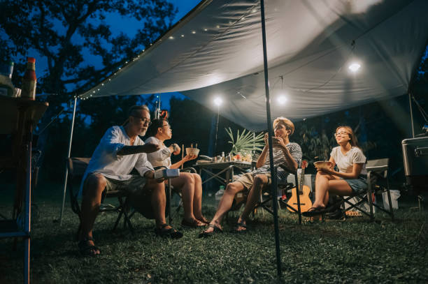 familia china asiática con 2 crías adolescentes disfrutando de la cena en la tienda de camping tarde por la noche - camping family vacations eating fotografías e imágenes de stock