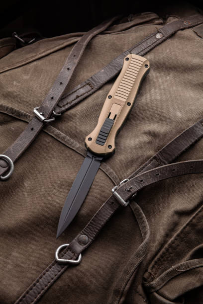 istock Modern folding knife on a rough canvas backpack. Melee weapons for self-defense and survival. A pocket knife on a rough dark background. 1320457463