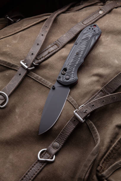 istock Modern folding knife on a rough canvas backpack. Melee weapons for self-defense and survival. A pocket knife on a rough dark background. 1320457468