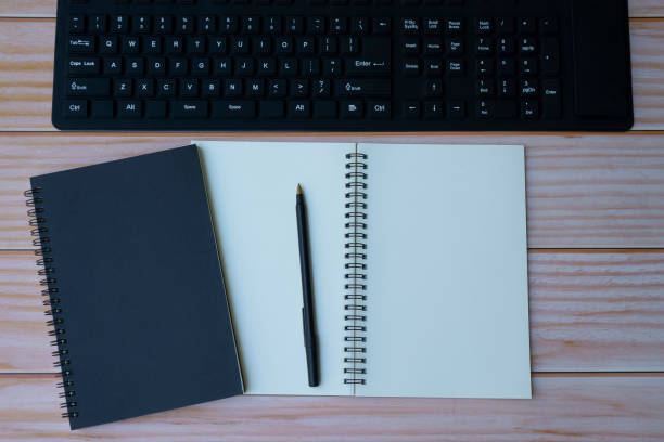 istock Home office with keyboard, note books and pen on wooden table. Space for text. Flat lay, top view 1320459221