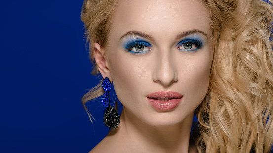 Beautiful young model with blonde hair and blue earrings