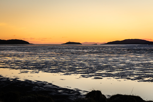 Golden winter sunset over Kirkcudbright Bay mudflats and the Dee estuary at low tide, with Ross Island and the isle of Man in the background, Dumfries and Galloway, Scotland