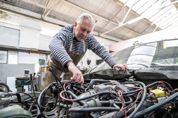istock Early 60s classic car restorer working on engine in garage 1320462262
