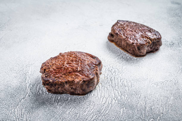 istock Grilled fillet mignon or tenderloin beef steak on kitchen table. White background. Top view 1320464145