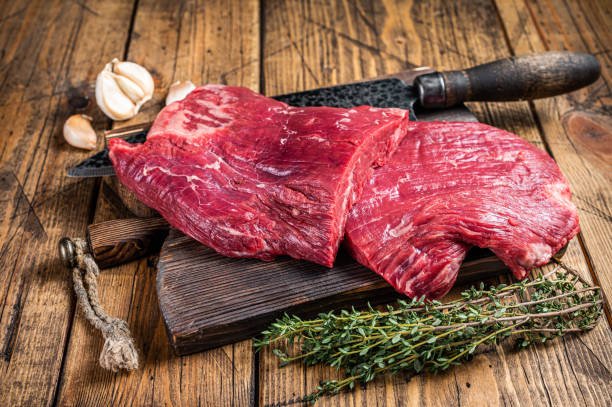 flank raw beef steaks on a butcher cutting board with knife. wooden background. top view - flank steak imagens e fotografias de stock