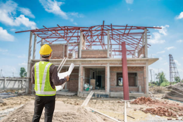 istock young professional engineer in protective helmet and blueprints paper at the house building construction site 1320464982