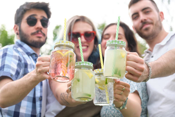 istock Group of four friends smiling and toasting with refreshing drinks looking at camera. 1320467330