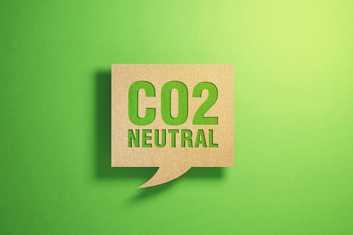 CO2 neutral written chat bubble made of recycled paper on green background. Horizontal composition with copy space. Sustainability concept.
