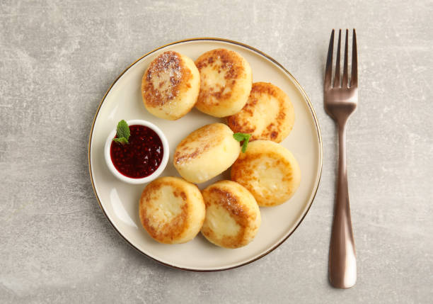 istock Delicious cottage cheese pancakes with jam and icing sugar on light grey table, flat lay 1320468395