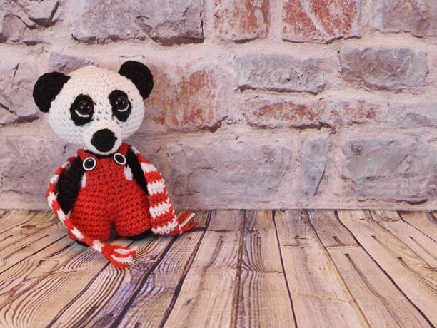 istock Knitted panda with untied scarf against a brick wall 1320468706