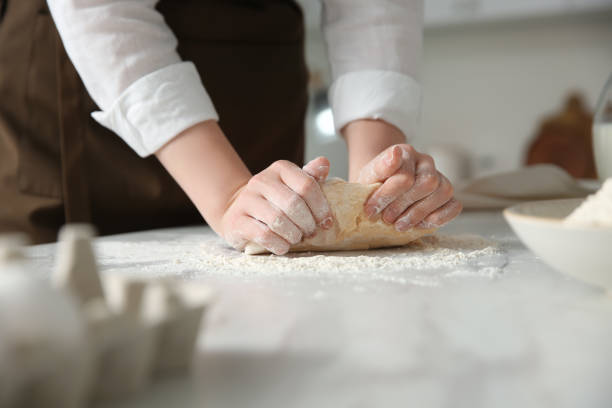 istock Woman kneading dough at table in kitchen, closeup 1320469304
