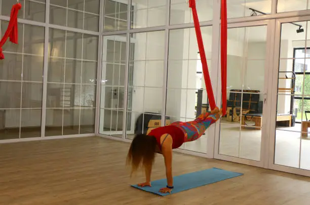 Woman instructor exercising poses for hammock yoga. Antigravity yoga for flexibility and healthy lifestyle. Aerial yoga to feel fit.