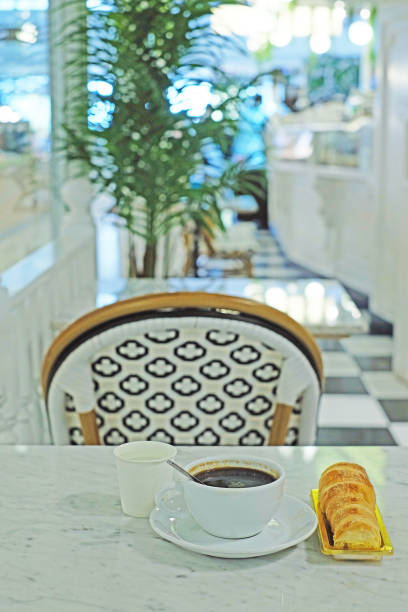 istock Hot coffee in white cup and cream croissant on stone table with blur bokeh background 1320471461