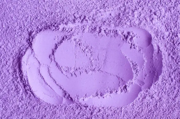 Photo of Purple clay powder (alginate face mask, body wrap, make-up eyeshadow) texture close up, selective focus. Abstract lavender background with brush storkes.