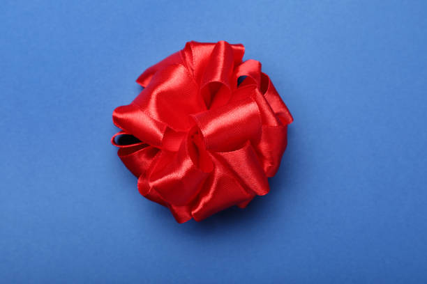 istock Red ribbon bow on blue background, top view 1320477438