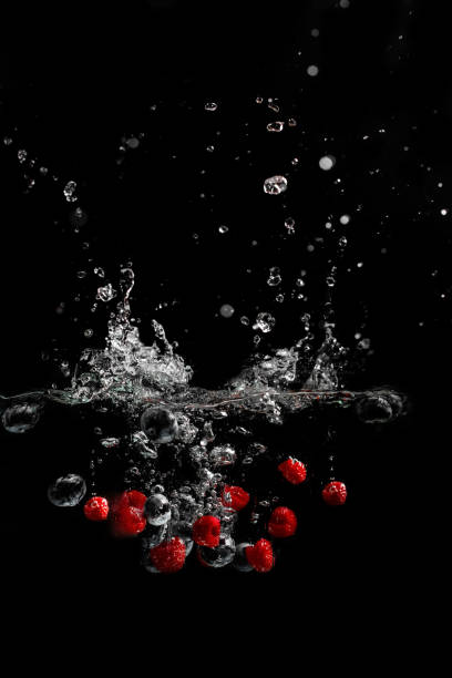 splash of water with fruits on a black