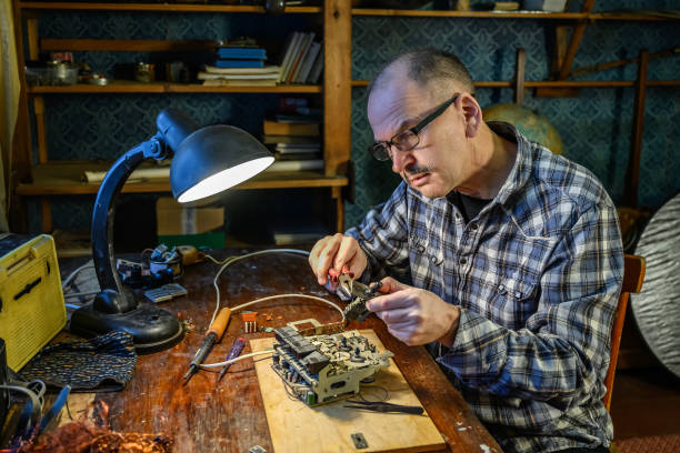 maschio adulto che ripara un vecchio ricevitore radio a casa - hardware audio foto e immagini stock