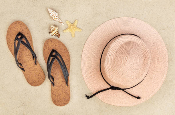 istock Flip flops with beach hat and seashells on sand. Top view. Vacation concept. 1320481470