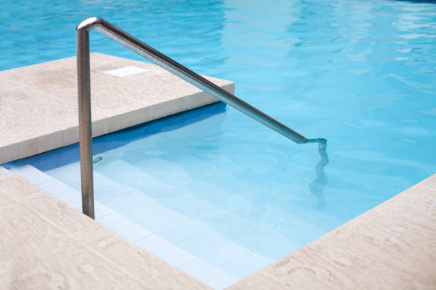 Swimming pool with grab and ladder at poolside. Nobody