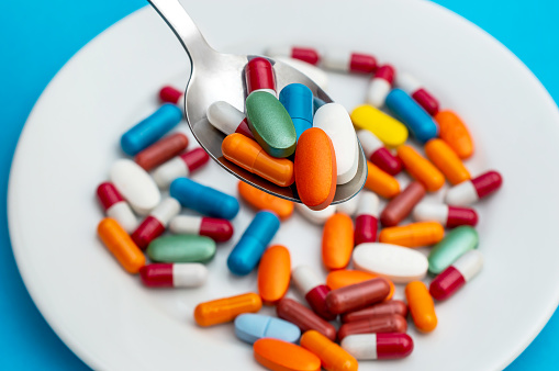 Full spoon of pills against plate with tablets.