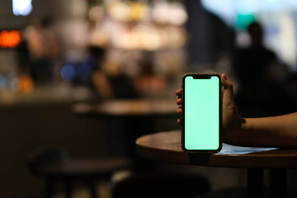 istock hand showing green screen phone on bar table at night 1320483412
