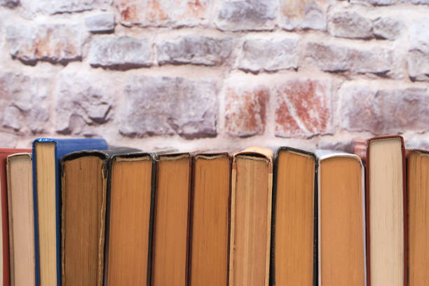istock Spines of old books stacked vertically on a brick wall background 1320488896
