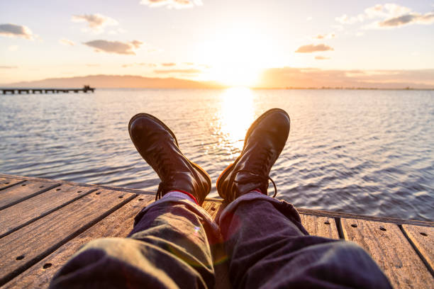 Picture of an explorer man boots captured in a beautiful pier during sunset.
