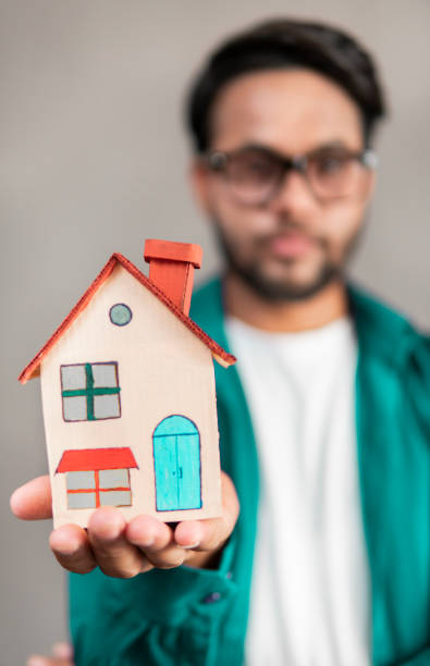 istock Young business man holding house model in hand. 1320491363
