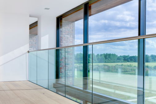 Modern architectural interior detail with wide ranging views over open countryside beyond glass balcony