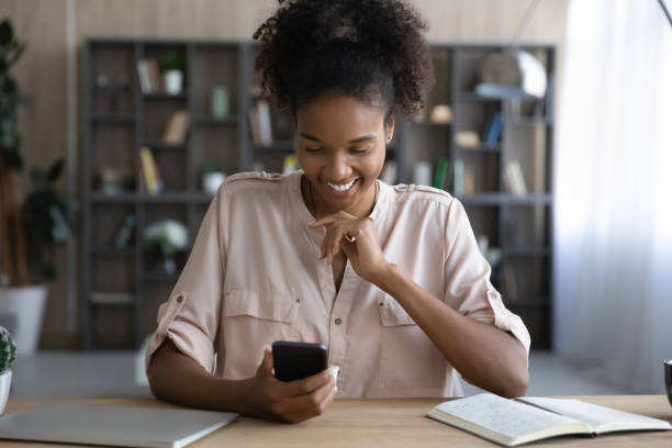 sorridente imprenditrice afroamericana che utilizza l'applicazione per smartphone. - women dependency business time foto e immagini stock