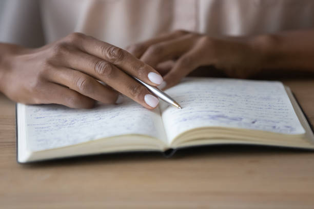 istock Young african woman reading notes in copybook. 1320497155
