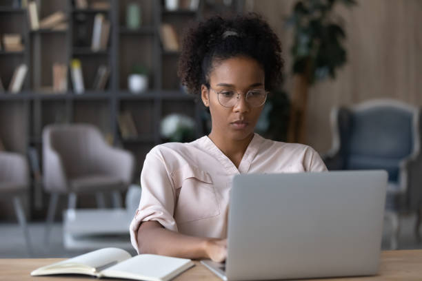 istock Concentrated young african woman in eyeglasses working on computer. 1320497168