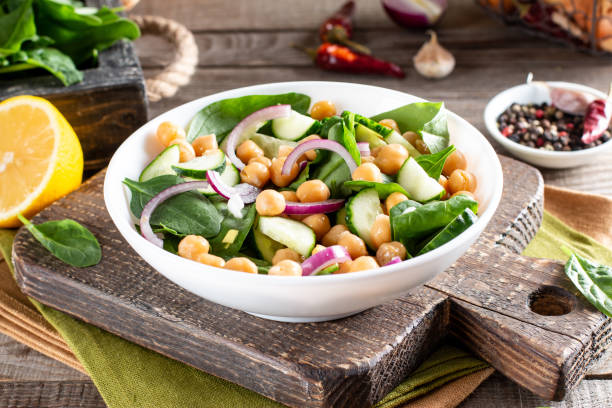 istock Chickpea salad with cucumber, spinach, parsley, onions and lemon in a plate on a served table. Tasty and healthy vegetarian food, oriental and Mediterranean cuisine. 1320497185