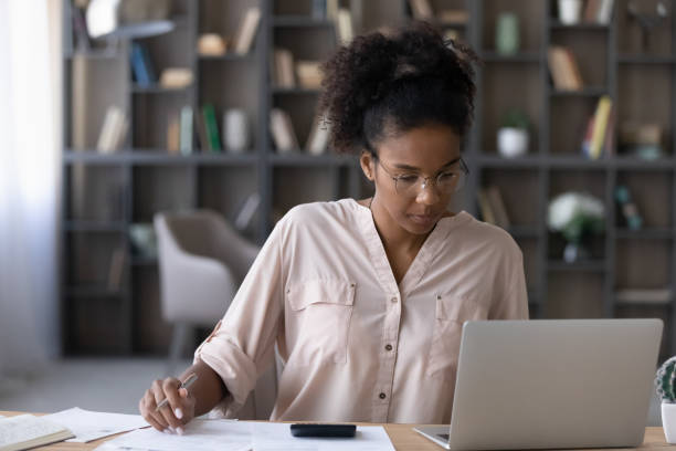 istock Concentrated young african ethnicity woman paying utilities online. 1320497792