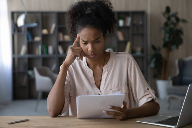istock Unhappy young african american woman looking through paper document. 1320497796