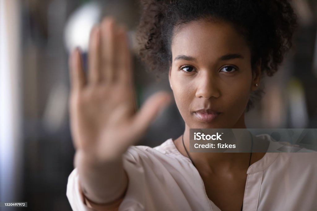 Confident african young woman showing stop signal. Head shot confident serious strong millennial generation african ethnicity woman looking at camera showing stop sign, denying abuse or bullying, protesting against racial or gender discrimination. Prevention Stock Photo