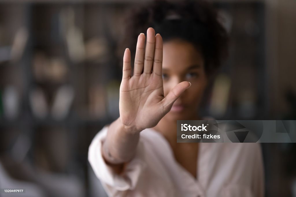 Serious african american woman protesting against bullying. Close up focus on female mixed race palm hand showing stop sign, serious african american woman protesting against bullying in society, sexual or racial discrimination, denying family abuse indoors. Women Stock Photo